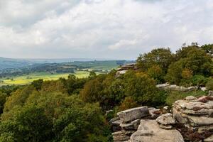 panoramico Visualizza di un' roccioso affioramento prospiciente un' lussureggiante verde valle con nuvoloso cieli. foto