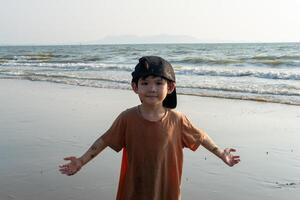 poco asiatico ragazzo giocando nel il sabbia a il mare spiaggia foto