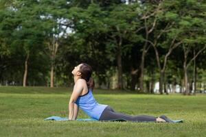 asiatico donna rilassante praticante cobra posa meditazione yoga e allungamento dentro il foresta per raggiungere felicità a partire dal interno pace saggezza per salutare mente e anima concetto foto