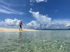 uomo a piedi su il bene sabbia di un' tropicale spiaggia su un' soleggiato giorno. foto