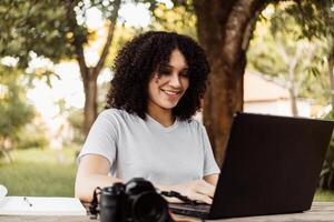 giovane donna con un' il computer portatile e telecamera nel un' parco. foto