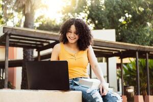 alunno ragazza Lavorando con un' il computer portatile nel un' verde parco foto