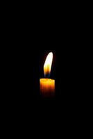 ardente bianca candela su il scuro, fiamma di candela su nero sfondo foto