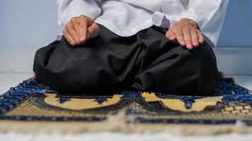 vicino su di musulmano uomo preghiere su preghiera stuoia e fare ultimo movimento su preghiera procedura foto