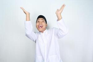 divertente asiatico musulmano uomo guardare su con sorpreso espressione e raccolta mano per presentazione isolato su bianca sfondo foto