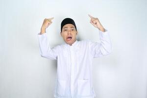 asiatico uomo musulmano puntamento sopra con scioccato espressione isolato su bianca sfondo foto