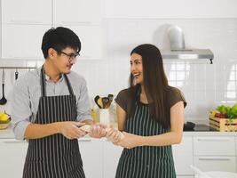 asiatico uomo indossare occhio bicchieri preparazione forno nel moderno cucina con bellissimo donna con lungo nero capelli. asiatico giovane coppia giocando con il Impasto quello essi fatto per Pizza. foto