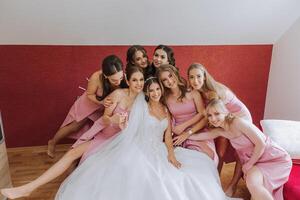 un' bellissimo sposa e sua damigelle d'onore siamo avendo divertimento nel il mattina. nozze celebrazione. contento ragazze a loro migliore gli amici nozze. un' bellissimo e elegante sposa con sua damigelle d'onore foto