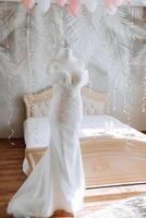 Camera da letto interno con nozze vestito preparato per il cerimonia. un' bellissimo lussureggiante nozze vestito su un' indossatrice nel un' Hotel camera. foto