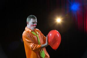 circo clown esegue numero. un' uomo nel un' clown attrezzatura con un' giocattolo. un' uomo nel un' clown attrezzatura con un' Palloncino foto