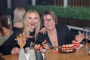 di mezza età donne nel un' bar Sorridi e Guarda a il telecamera. foto