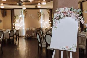un originale floreale decorato tavola con un' bianca foglio, contro il fondale di un' abbandonato nozze sala nel il sfondo. con un iscrizione piatto. foto