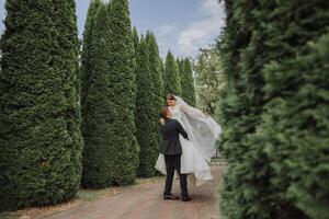 il sposo sollevato il sposa nel il suo braccia e è girando nel un' bellissimo giardino. sposa e sposo danza nel il Giardino dietro la casa. foto