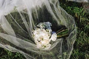 un elegante e bellissimo nozze mazzo di bianca fiori bugie su il della sposa velo. alto qualità foto