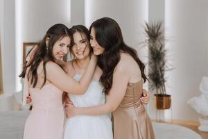 un' bellissimo sposa e sua damigelle d'onore siamo avendo divertimento nel il mattina. nozze celebrazione. contento ragazze a loro migliore gli amici nozze. un' bellissimo e elegante sposa con sua damigelle d'onore foto