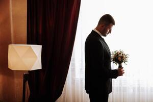 ritratto di un' giovane sposo a casa prima il nozze cerimonia. un' bello uomo vestito nel un' classico completo da uomo. maschio ritratto. foto