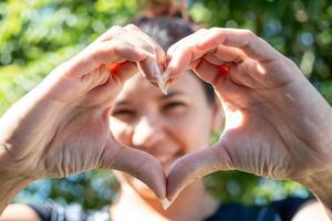 latino donna fabbricazione un' cuore con sua mani foto