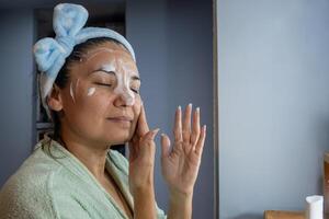latino ragazza si applica detergente schiuma su sua viso. foto