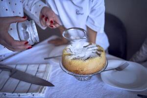 famiglia di tre, madre, adolescenziale figlia e poco figlio, mangiare torta nel pigiama a un' tavolo con tulipani foto