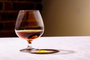 il bagliore a partire dal il bicchiere di francese Brandy riflessa su bianca linguetta foto