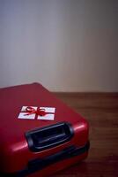un' regalo certificato nel rosso e bianca colori su un' rosso valigia per viaggio foto