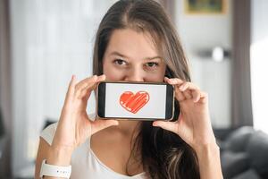 mondo Salute giorno concetto. giovane donna mostrando illustrazione di cuore su sua smartphone, illustrare il importanza di cardiovascolare Salute consapevolezza su internazionale Salute osservazione foto