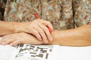 anziano donna giocando sudoku puzzle gioco per trattamento demenza prevenzione e alzheimer patologia. foto