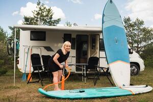 un' donna si gonfia un' sup-board per nuoto vicino sua camper foto