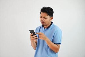 triste viso con Tenere Telefono giovane asiatico uomo indossare blu polo t camicia isolato su bianca sfondo. irritata viso espressioni foto