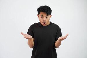 stupito o scioccato giovane asiatico uomo Aperto mano con Aperto bocca indossare nero t camicia isolato su bianca sfondo foto