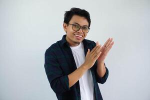 giovane asiatico uomo mostrando contento espressione battimani con per dare apprezzamento isolato su bianca sfondo foto