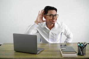 giovane asiatico uomo d'affari nel un' posto di lavoro ascoltando per qualcosa di mettendo mano su il orecchio indossare bianca camicia isolato su bianca sfondo foto
