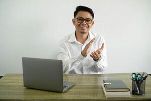 sorridente giovane asiatico uomo d'affari nel un' posto di lavoro Applaudire dopo presentazione nel un' conferenza, indossare bianca camicia con bicchieri isolato foto