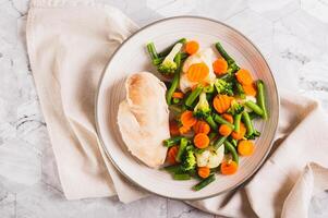 vicino su di misto verdure e al vapore pollo Seno su un' piatto su il tavolo superiore Visualizza foto