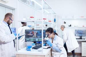 assistente fare ricerca utilizzando microscopio e scienziato assunzione Appunti su tavoletta pc. squadra di ricercatori fare farmacologia ingegneria nel sterile laboratorio per assistenza sanitaria industria con africano assistente nel il sfondo. foto