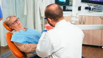 specialista ortodontista Tenere il dentale mascella A proposito di con paziente. dentista dimostrando professionale spazzolatura di denti con un' spazzolino, movimenti quello porzione mantenere il tuo denti sano. foto