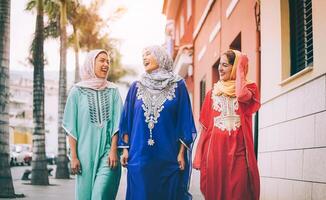 contento musulmano donne a piedi nel il città centro - arabo giovane ragazze avendo divertimento la spesa tempo e ridendo insieme all'aperto - concetto di le persone, cultura e religione foto