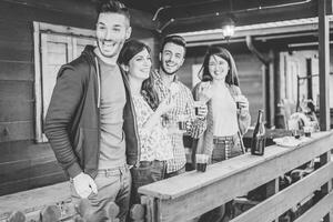 contento amici godendo un' incontro potabile rosso vino e mangiare insieme nel il Giardino dietro la casa - giovane persone avendo divertimento con bevande in piedi al di fuori casa - amicizia, stile di vita, gioventù concetto foto