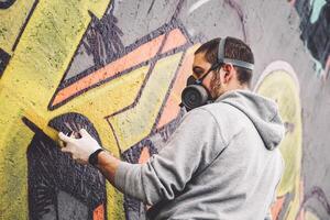 strada graffiti artista pittura con un' colore spray può un' graffiti su il parete nel il città - urbano, stile di vita strada arte concetto foto