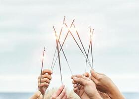 vicino su mani di gruppo di contento amici avendo divertimento festeggiare con sparklers fuochi d'artificio all'aperto - gioventù, celebrare, festa stile di vita concetto foto