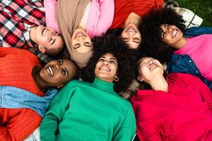contento giovane Multi etnico donne avendo divertimento dire bugie su parco erba - diversità e amicizia concetto foto