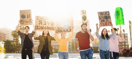 manifestanti gruppo protestare contro plastica inquinamento e clima modificare - multirazziale persone combattente su strada Tenere banner su ambienti disastri - globale riscaldamento concetto foto