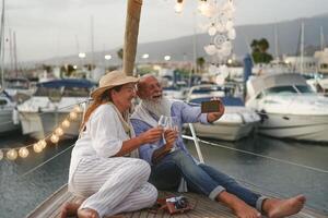 anziano coppia tostatura Champagne mentre assunzione autoscatto su barca a vela vacanza - contento maturo persone avendo divertimento festeggiare nozze anniversario su barca viaggio - amore relazione e viaggio stile di vita concetto foto