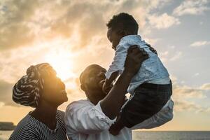 contento africano famiglia avendo divertimento su il spiaggia durante estate vacanze - genitori amore concetto foto