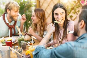 contento amici pranzare con salutare cibo nel bar ristorante - giovane persone avendo brunch pasto mangiare e potabile frullati fresco frutta nel Vintage ▾ bar - Salute tendenze stile di vita concetto foto