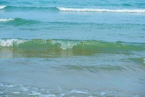 onde su il spiaggia. blu mare onda. blu acqua superficie struttura con increspature, schizzi, e bolle. astratto estate bandiera sfondo acqua onde nel luce del sole con copia spazio cosmetico idratante. foto