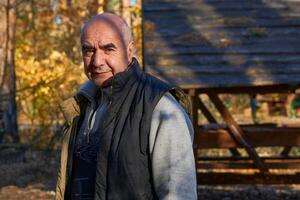 allegro anziano pensionato nel un' caldo veste a un' campeggio su un autunno picnic foto