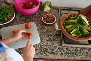 femmina capocuoco affettare pomodori, cucinando vegetariano tagine, secondo per tradizionale marocchino ricetta nel il cucina a casa foto