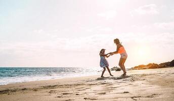 contento amorevole famiglia madre e figlia avendo divertimento su il spiaggia a tramonto - mamma giocando con sua ragazzo Il prossimo vedere nel vacanze - genitore, vacanza, famiglia stile di vita concetto foto