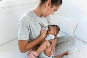 contento madre l'allattamento al seno sua poco bambino su letto - famiglia e maternità concetto foto